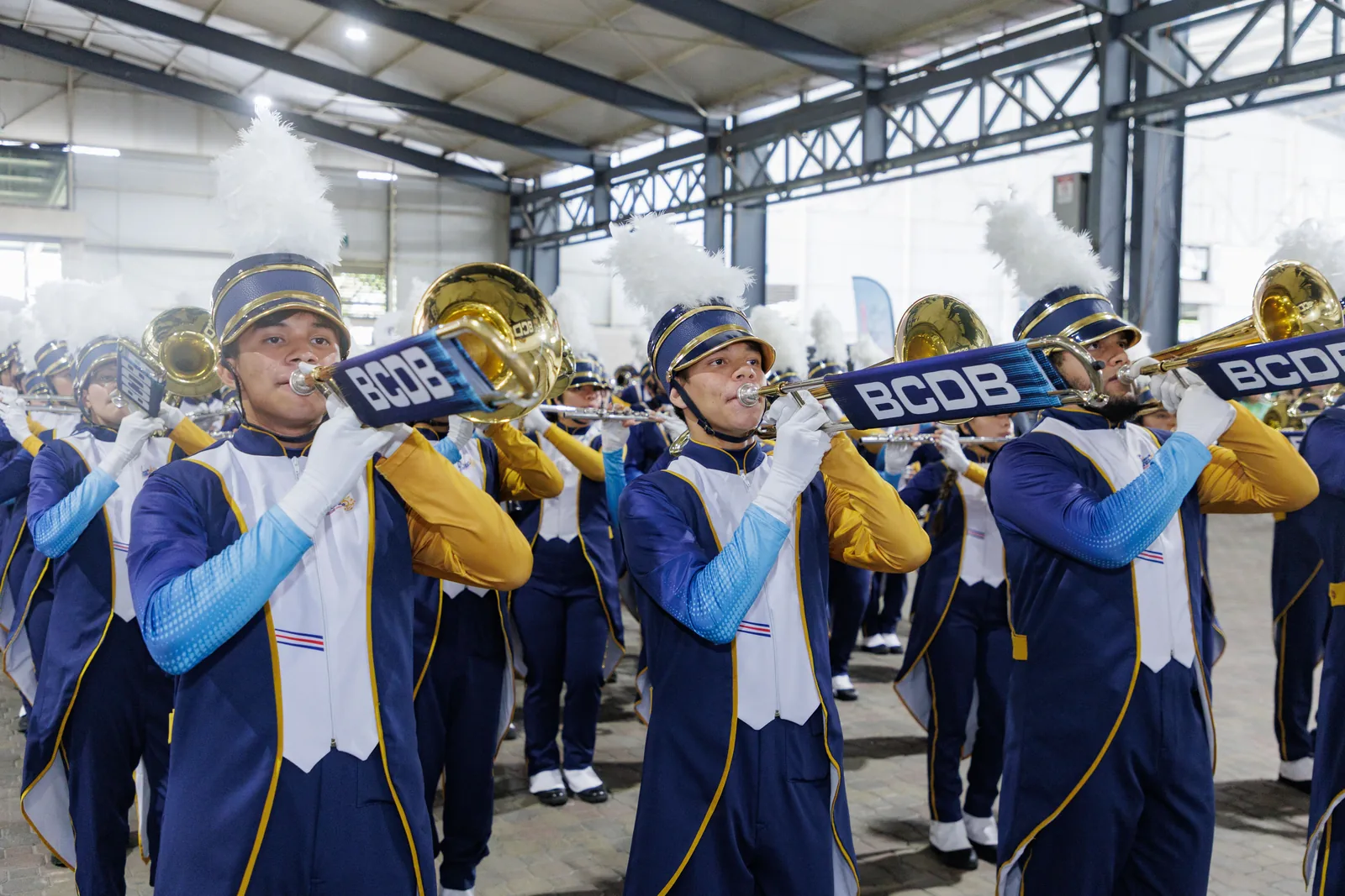Banda musical con uniformes azules y blancos tocando instrumentos de viento en la feria